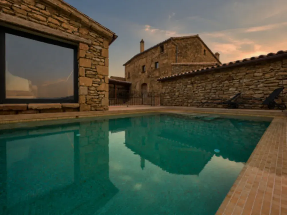 Piscina y fachada de piedra de la casa UMBRAL
